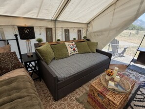 A tent interior with a sofa, a lamp, and a small table with decorative items.