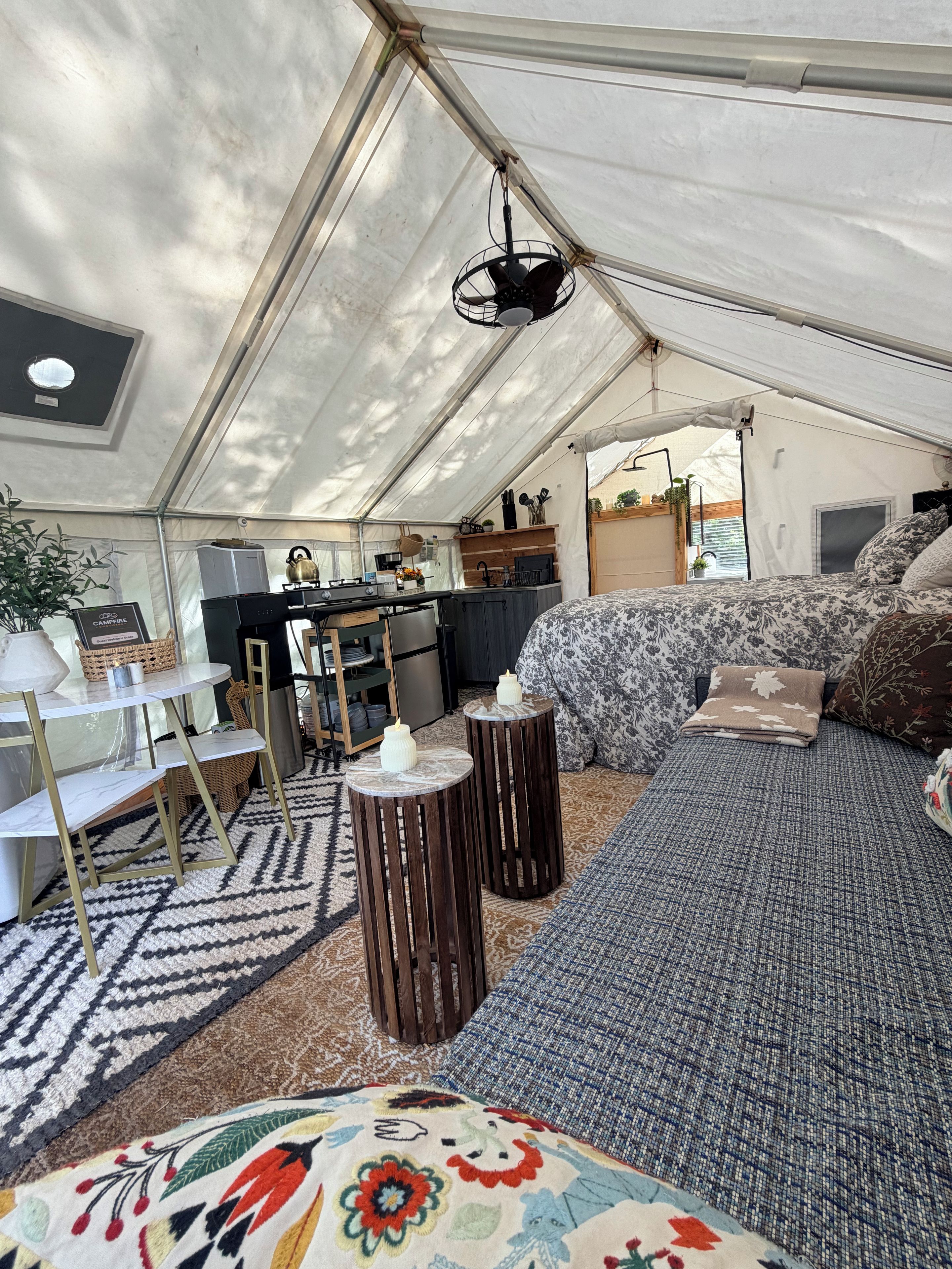 Un alloggio in tenda dotato di angolo cottura, zona salotto e un letto con coperta decorata.