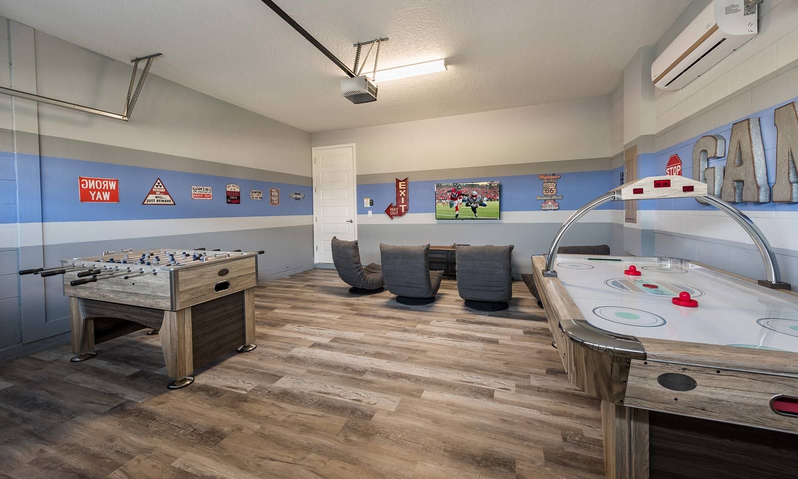 A room with a foosball table, a pool table, and a bar area.