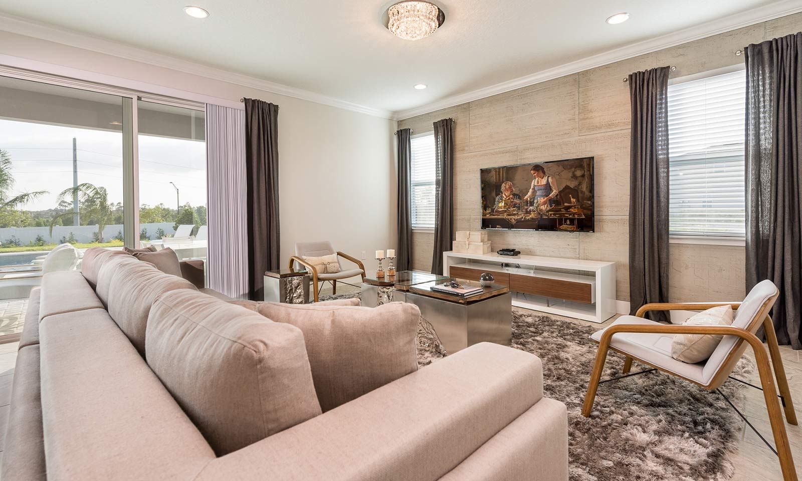A modern living room with a beige sofa, a coffee table, a TV, and a fireplace.