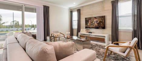 A modern living room with a beige sofa, a coffee table, a TV, and a fireplace.