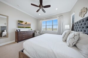 Quarto com cama, penteadeira, cadeira, ventilador de teto e janela com cortinas.