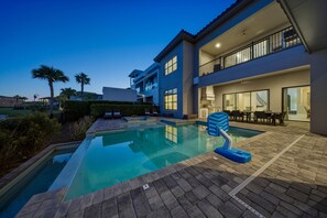 Ein modernes, zweistöckiges Gebäude mit Swimmingpool und Außenbereich mit Sitzgelegenheiten.