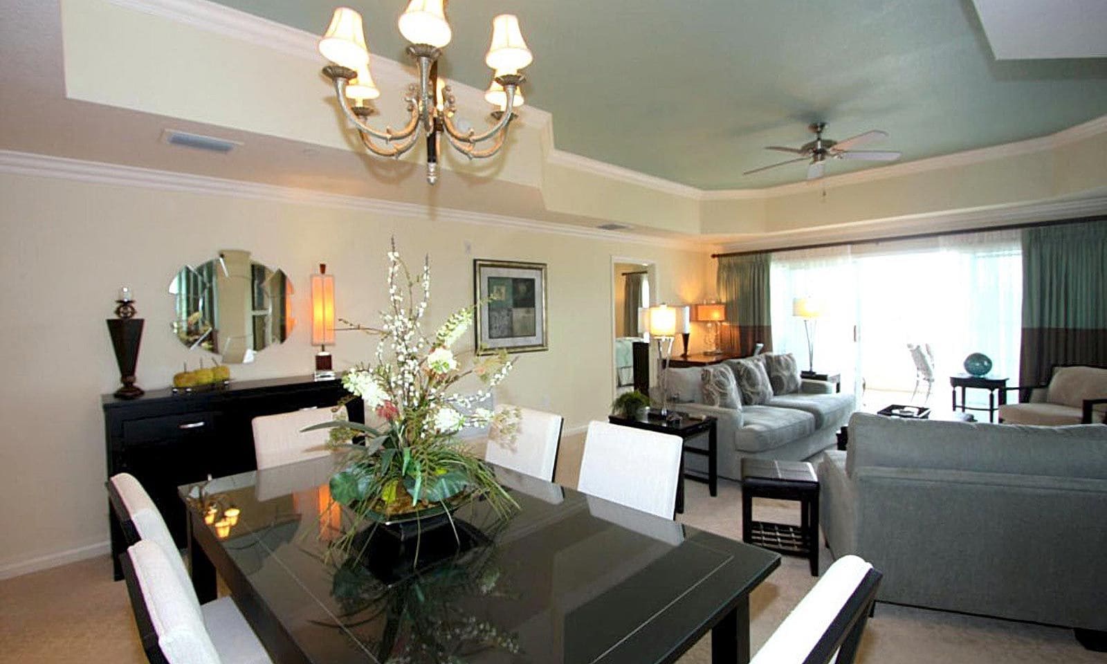 A modern living room with a dining table, sofa, and a chandelier.
