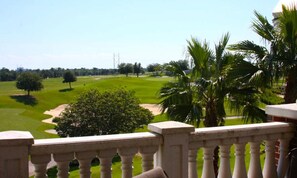 Blick auf einen Golfplatz mit Palmen und blauem Himmel.