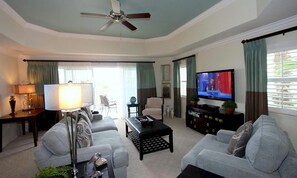 Ein Wohnzimmer mit Deckenventilator, Fernseher, Sofa, Couchtisch und Lampe.