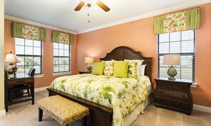 A bedroom with a bed, two nightstands, a bench, a ceiling fan, and two windows with curtains. - Sleek Home With Stunning Game Room at Reunion (Kissimmee)