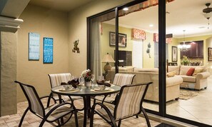 A dining area with a round table, chairs, and a glass partition. There are framed pictures on the wall and a sofa in the background. - Sleek Home With Stunning Game Room at Reunion (Kissimmee)
