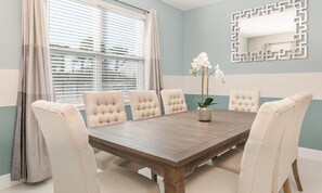 A dining room with a wooden table, six upholstered chairs, a potted plant, and a decorative mirror on the wall. - Marvelous Retreat With Themed Bedrooms at Encore (Kissimmee)