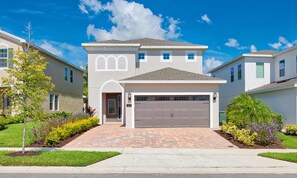 A two-story residential building with a garage, a driveway, and a well-maintained lawn. - Encore Villa With Pool, 10 min to Disney (Kissimmee)