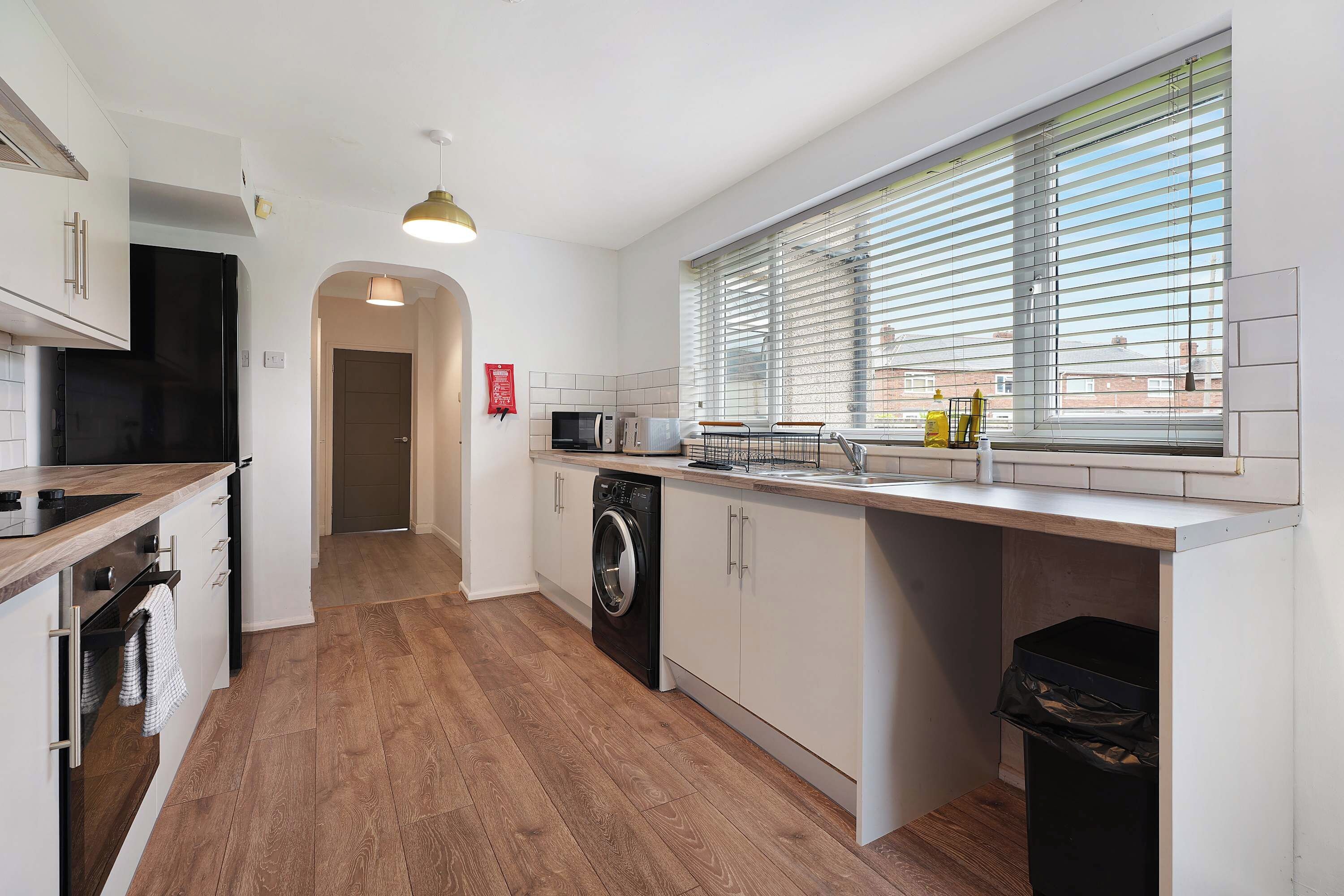 A modern kitchen with a central island, a microwave, a dishwasher, and a window with blinds.