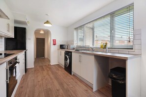 A modern kitchen with a central island, a microwave, a dishwasher, and a window with blinds. - Chic 4BR Contractor Stay for 7+WiFi | Stay With Us (Stockton-on-Tees)