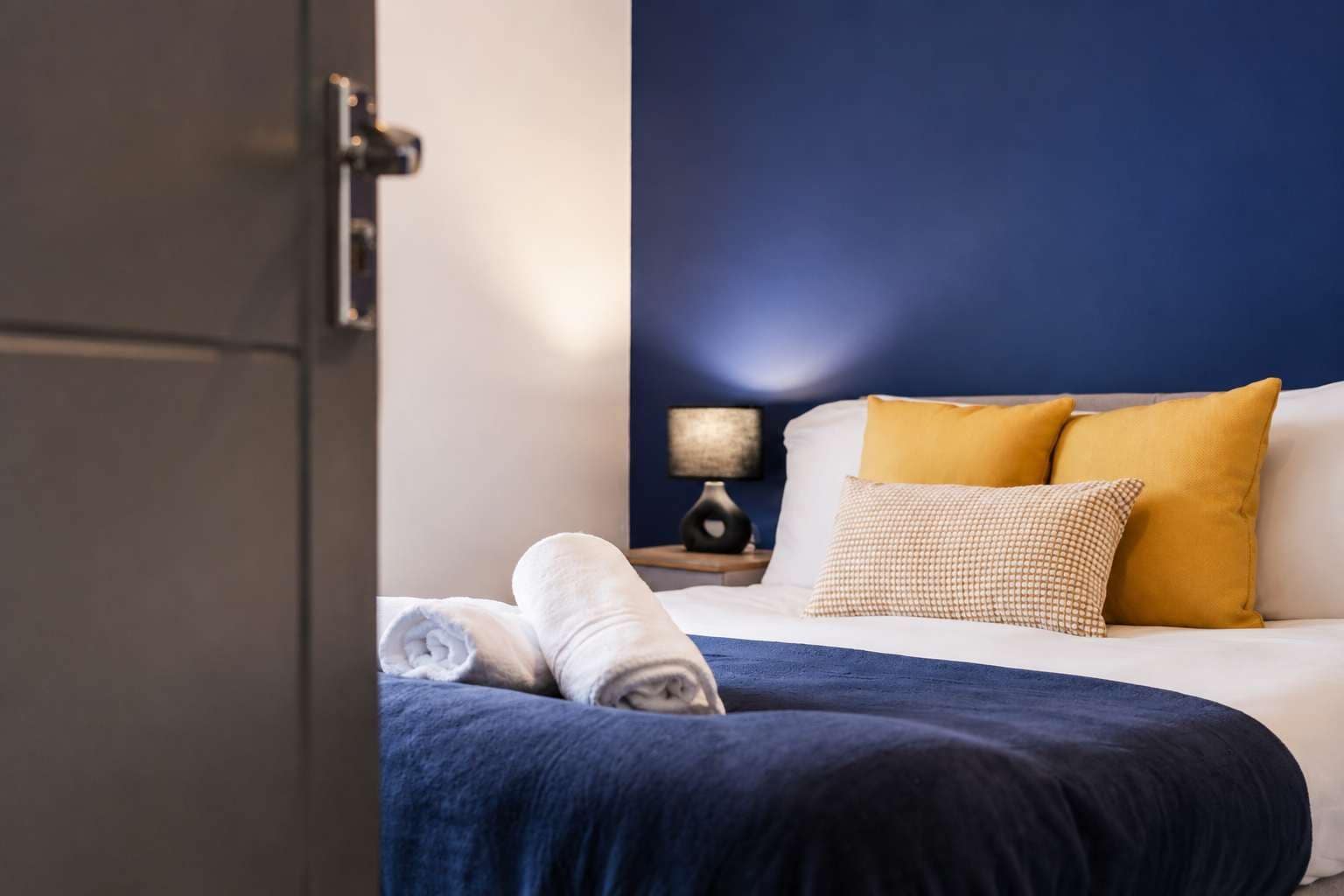 Une chambre d’hôtel avec un lit, une table de chevet et une lampe.