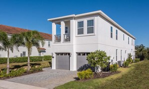 A modern two-story house with a white exterior, a garage, and a paved driveway. - Stylish Villa With Unreal Themed Bedroom at Reunion (Kissimmee)