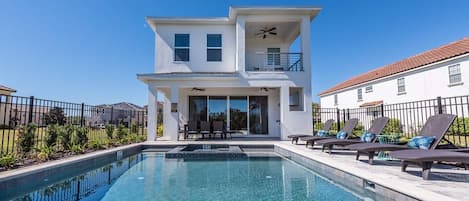 A modern two-story house with a swimming pool, outdoor seating, and a balcony.