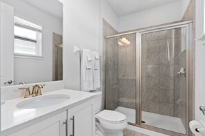 Ein modernes Badezimmer mit großem Spiegel, Waschbecken, Toilette und begehbarer Dusche.