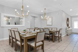 Ein Esszimmer mit großem Tisch, Stühlen und Pendelleuchten.