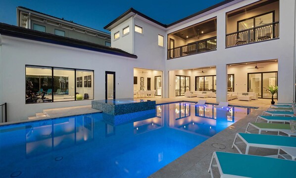 Une résidence moderne dotée d’une piscine, de plusieurs balcons et d’un intérieur bien éclairé.