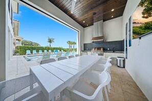 Un espace extérieur aménagé pour les repas, avec vue sur la piscine, un barbecue et un panorama sur les environs.