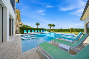 Une piscine avec des chaises longues, un ciel dégagé et un jardin aménagé.