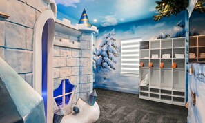 A children's play area with a snowy landscape mural, a slide, and a storage unit with folded towels. - Luxurious Mansion With Infinity Pool at Reunion (Kissimmee)