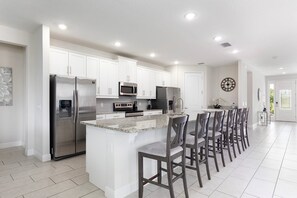A modern kitchen with white cabinets, stainless steel appliances, and a granite countertop. - The Themepark Palace With Home Theater at Encore (Kissimmee)