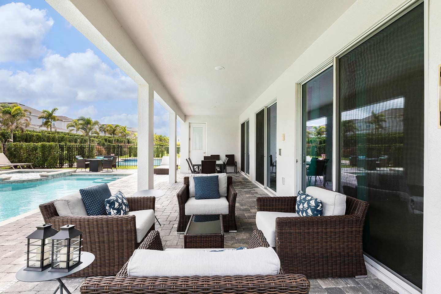 A covered outdoor seating area with wicker furniture, a pool, and a view of the surrounding landscape.