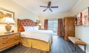 A well-appointed bedroom with a large bed, a wooden dresser, a bench, and a ceiling fan. - Spacious Elegant Condo With Private Balcony at Reunion (Kissimmee)
