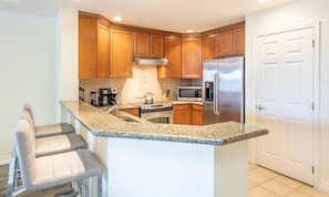 A kitchen with wooden cabinets, a stainless steel refrigerator, a microwave, and a built-in oven. - Spacious Elegant Condo With Private Balcony at Reunion (Kissimmee)
