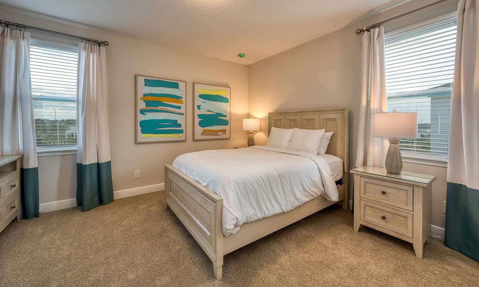 A bedroom with a bed, bedside tables, a lamp, and abstract art on the wall.