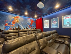 A home theater with leather reclining seats, a starry ceiling mural, and movie posters on the wall. - The Cheerful Cinematic Haven at Encore Resort (Kissimmee)