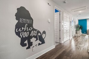 Un couloir agrémenté d’un autocollant mural inspirant, de portes blanches et d’un mur d’accent bleu.