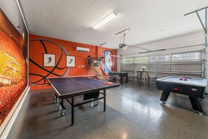 Une salle de loisirs équipée d’une table de ping-pong, d’un billard et d’une fresque murale représentant un terrain de basket.