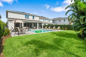 A two-story house with a swimming pool, outdoor seating, and lush greenery. - The Cheerful Cinematic Haven at Encore Resort (Kissimmee)