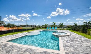 A rectangular swimming pool with a hot tub, surrounded by a paved deck and a black fence. - Marvelous Villa With Galactic Themed Bedroom at Encore (Kissimmee)