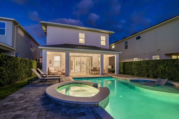 Ein modernes Haus mit Swimmingpool, einer überdachten Terrasse und einem gepflegten Garten.
