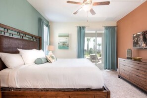 A bedroom with a bed, a nightstand, a ceiling fan, a window with curtains, a painting, and a view of the outdoors. - Encore Villa: Pool, Spa, Minutes to Disney (Kissimmee)