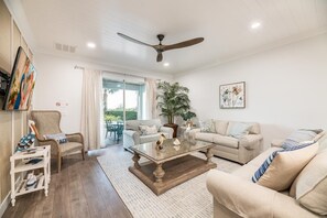 A living room with a ceiling fan, a coffee table, two sofas, a chair, a side table, and a large potted plant. - Encore Villa: Pool, Spa, Minutes to Disney (Kissimmee)