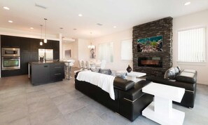 A modern living room with a black sofa, a white coffee table, and a stone fireplace. - Ultra-modern Villa On Golf Course at Reunion (Kissimmee)