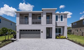 A modern two-story house with a garage, a balcony, and a well-maintained lawn. - Stylish Home With Galactic Themed Bedroom at Encore (Kissimmee)