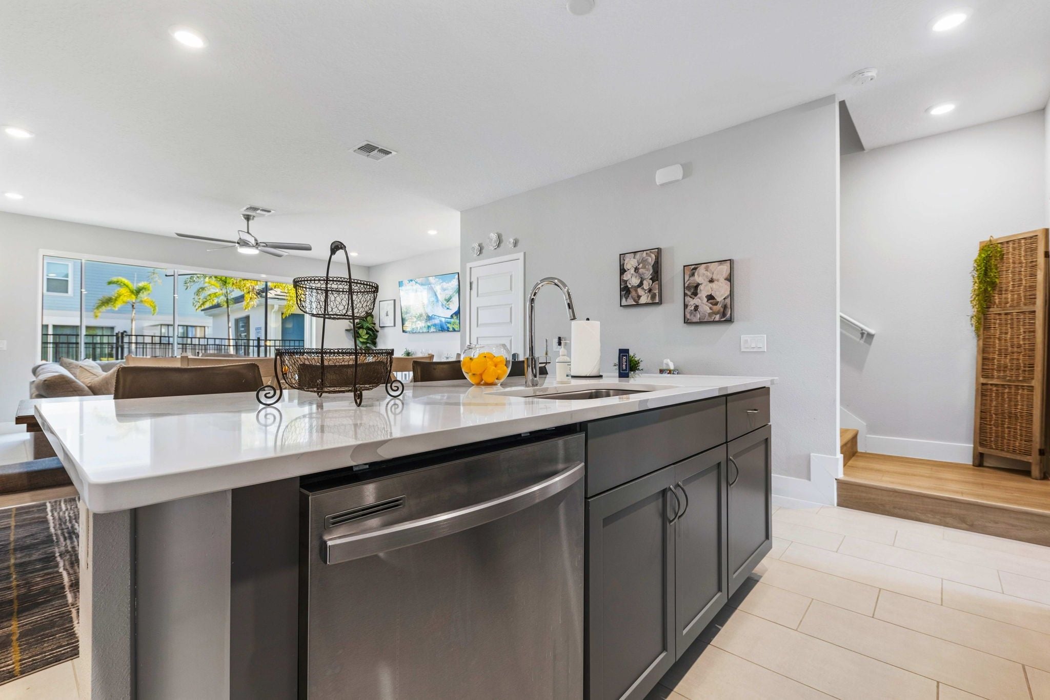 A modern kitchen with a stainless steel dishwasher, a double sink, and a large island.