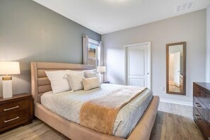 Ein Schlafzimmer mit einem Bett, Nachttischen, einer Kommode und einem Spiegel.