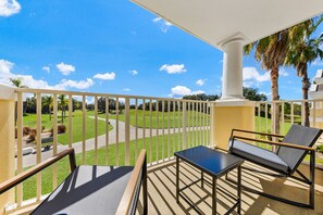 Un balcon donnant sur un terrain de golf, avec une table et deux chaises.