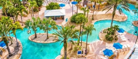 A resort with multiple swimming pools, palm trees, and lounge areas.