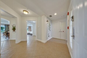 A spacious hallway with a tiled floor, white walls, and a door with a security lock. - The Golf Vista Townhome at Reunion (Kissimmee)