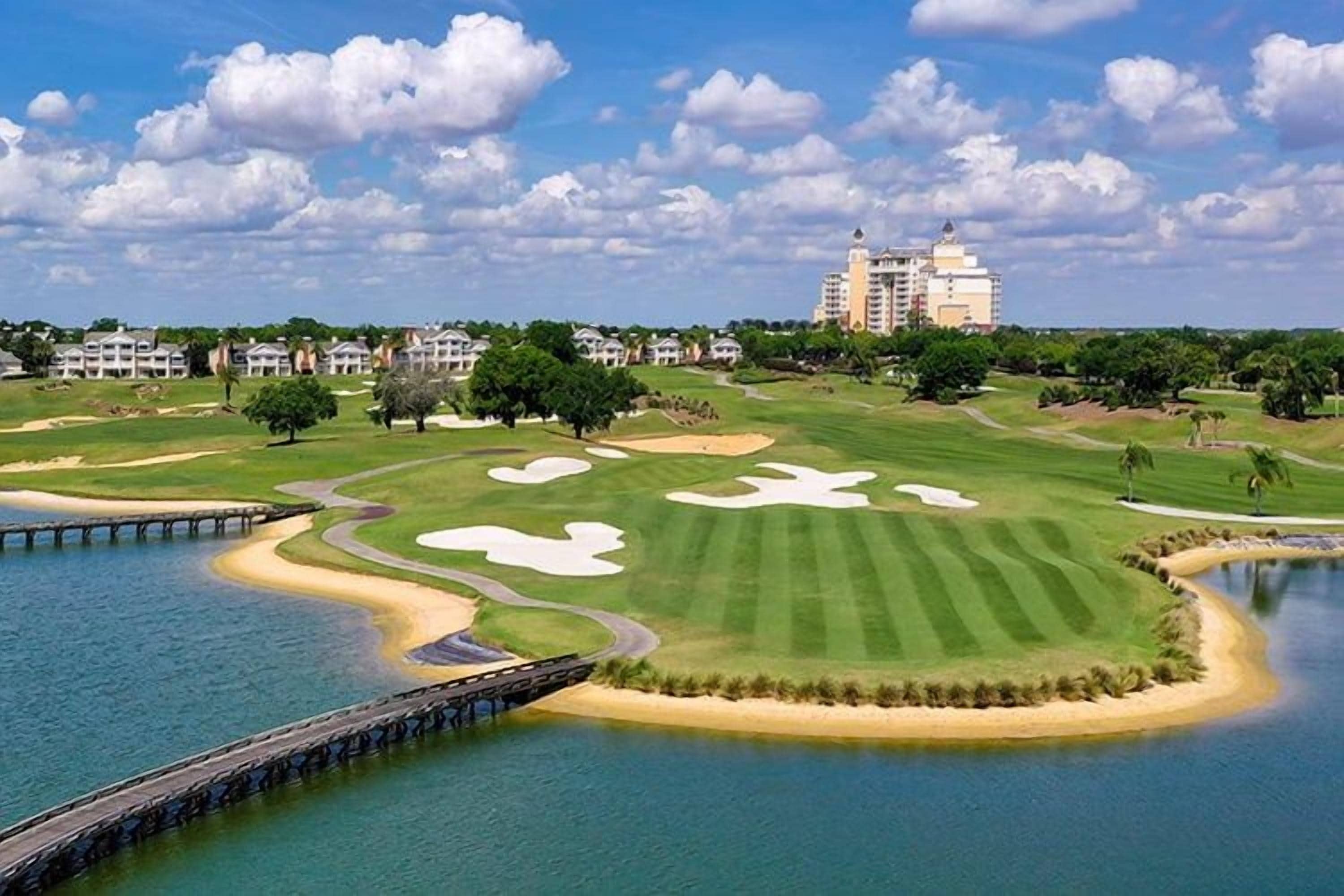 Un campo de golf con búnkeres, una masa de agua y un puente.
