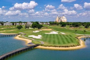 A golf course with bunkers, a water body, and a bridge. - The Golf Vista Townhome at Reunion (Kissimmee)