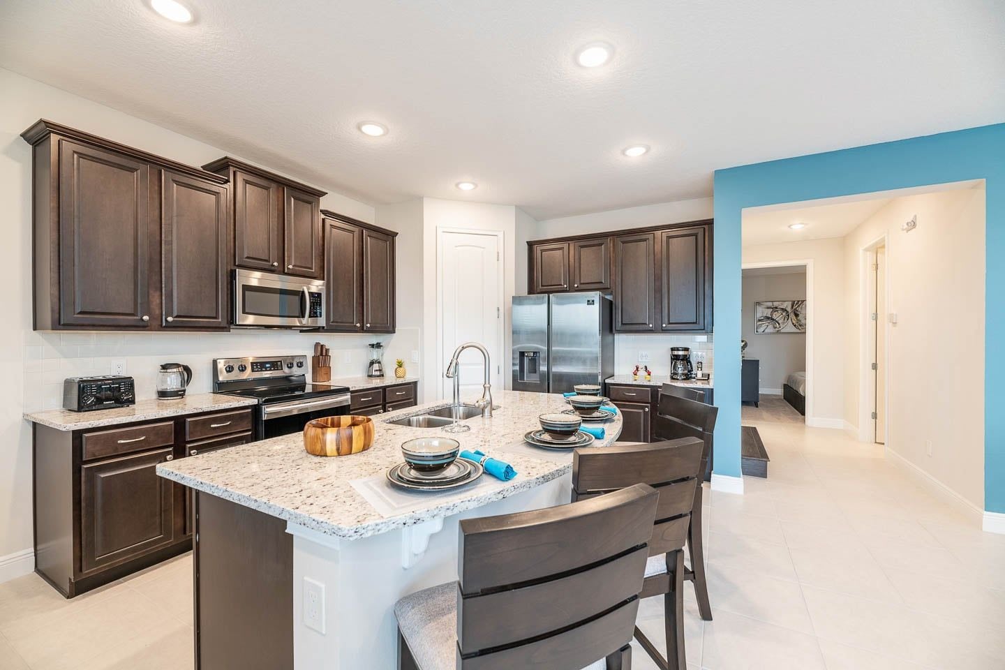 A modern kitchen with dark wood cabinets, stainless steel appliances, and a granite countertop.