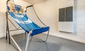 A basketball court with a blue and white net, a basketball hoop, and a wall-mounted electrical panel. - Gleaming Villa With Themed Bedrooms at Encore (Kissimmee)