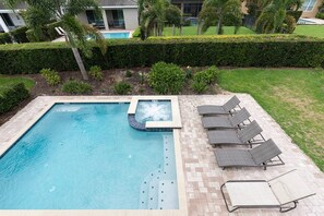 A rectangular swimming pool with a hot tub, surrounded by a brick patio and lounge chairs. - Encore Villa: Pool & Spa, 4 Blocks to Waterpark (Kissimmee)